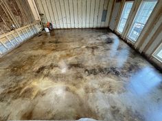 an empty room that has been painted with brown and white paint on the floor, in front of two windows