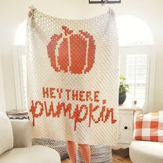 a woman is holding up a crocheted blanket with the words hey there pumpkin on it