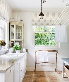 a kitchen with white cabinets and marble counter tops in front of a large window that looks out onto the outdoors