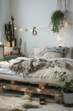 a bed made out of wooden pallets with lights strung from the ceiling and plants