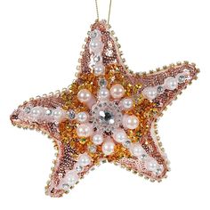 a pink and gold star ornament with pearls