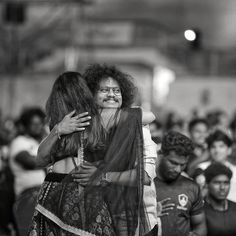 black and white photograph of two women hugging each other in the middle of a crowd