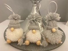 three small stuffed animals sitting on top of a metal plate next to a silver vase