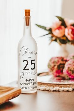 a bottle of wine sitting on top of a table next to a plate with flowers