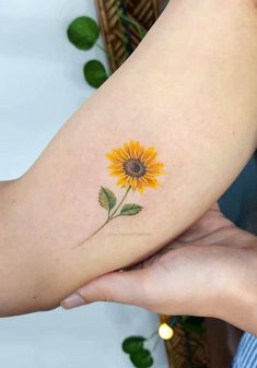 a woman's arm with a sunflower tattoo on it