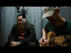 two men sitting next to each other with guitars in front of their faces and one holding a guitar