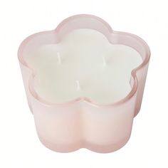 a pink candle holder with a flower design on the front and bottom, holding a lit candle