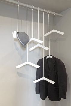 a coat and hat hanging from hooks on a wall next to a jacket hanger