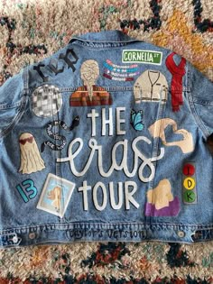 a jean jacket with the words the eras tour written on it and various stickers