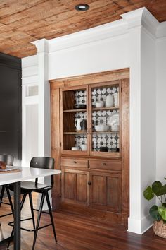 a dining room table with chairs and a china cabinet in the corner next to it