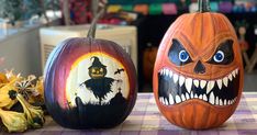 two pumpkins with painted faces on them sitting on a table next to each other