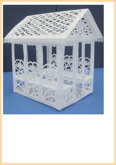 a white plastic birdcage with cut outs on the top and sides, in front of a blue background