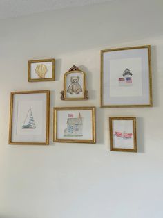 there are many pictures on the wall with gold frames around them, including a teddy bear and seashell