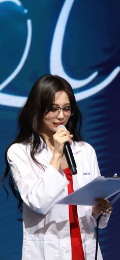 a woman in white shirt and red tie holding a microphone