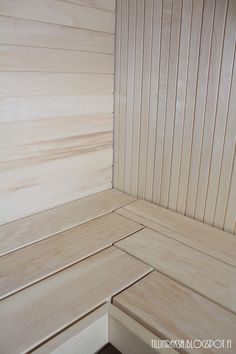 a wooden bench sitting next to a wall with wood slats on the walls and floor