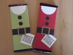 two candy bar wrappers decorated like santa clause and elf with tags on them sitting on a table