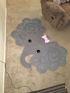 an elephant rug is laying on the floor next to a couch with a pink bow