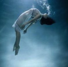 a woman floating in the water with her head above the water's surface