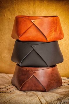 four different colored leathers are stacked on top of each other in this photo, one is brown and the other is black