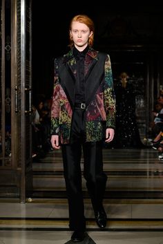 a man in a tuxedo walks down the runway wearing black pants and a floral jacket