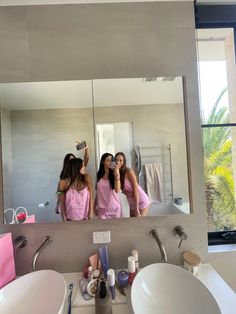 two girls in pink dresses are looking at their reflection in the mirror