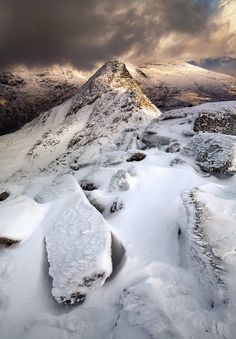 snow covered mountains under a cloudy sky on a snowy day in the scottish highlands, uk