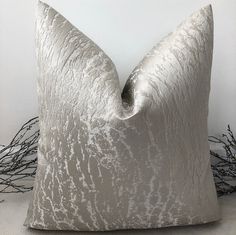 a white pillow sitting on top of a table next to dry grass and branches in the background