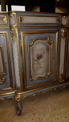 an ornate blue and gold sideboard with flowers painted on the doors, in a room