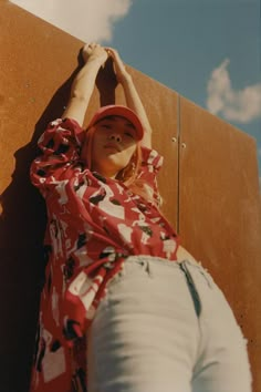 a woman leaning up against a wall with her hands on the back of her head