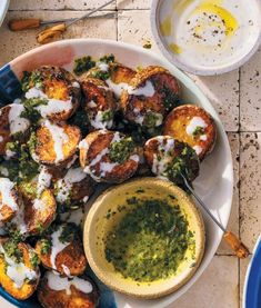 a white plate topped with food next to a bowl filled with pesto and cheese