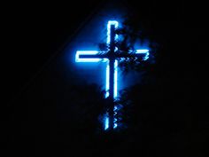 a cross is lit up in the dark with blue lights on it's sides