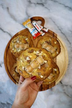 a person is holding up some cookies on a wooden platter with candy bars in the background