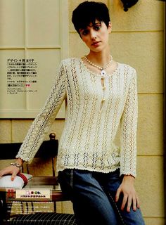 a woman standing next to a table with a basket on it's lap and wearing a white sweater