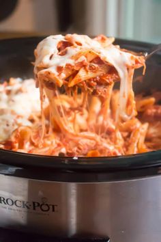 a crock pot filled with lasagna sauce and cheese is being lifted from the slow cooker