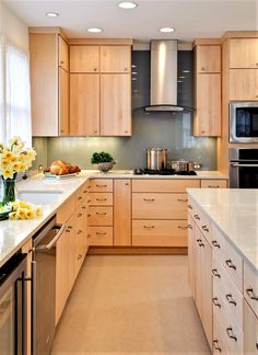 a large kitchen with wooden cabinets and stainless steel appliances, along with yellow flowers in vases