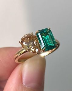 someone is holding an emerald and diamond ring