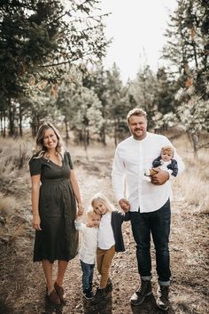 a man, woman and two children are standing in the woods