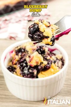 a blueberry dump cake in a white bowl with a fork sticking out of it