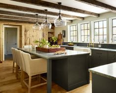 a kitchen with an island and wooden beams in the ceiling, along with two chairs