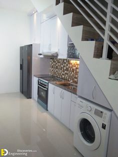 an empty kitchen and laundry room with stairs leading up to the upper floor, next to a washer and dryer