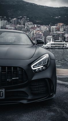 the front end of a black mercedes sports car parked in front of a cityscape