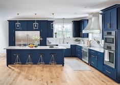 a large kitchen with blue cabinets and white counter tops, an island in the middle