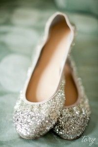 a pair of silver glittered shoes sitting on top of a green bedding covered floor