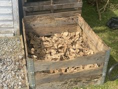 a pile of wood sitting in a wooden crate on top of some grass next to a building