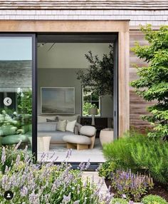 an open living room with glass doors leading to the outside patio and garden area in front of it