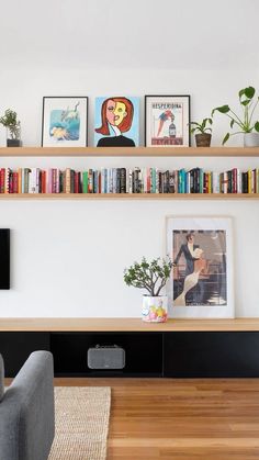 a living room with bookshelves and pictures on the wall above it, along with two couches