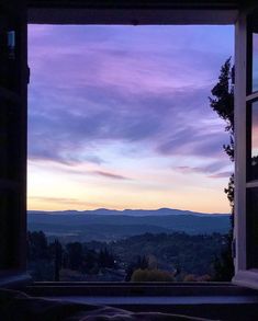 an open window with the view of mountains in the distance at sunset or sunrise time