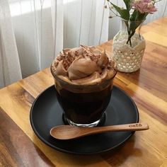 there is a cup of ice cream on the table next to a vase with flowers