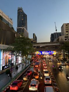 a city street filled with lots of traffic next to tall buildings at dusk or dawn