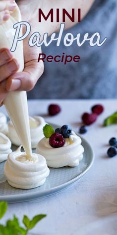 mini pavlova recipe on a plate with berries and whipped cream being drizzled over it